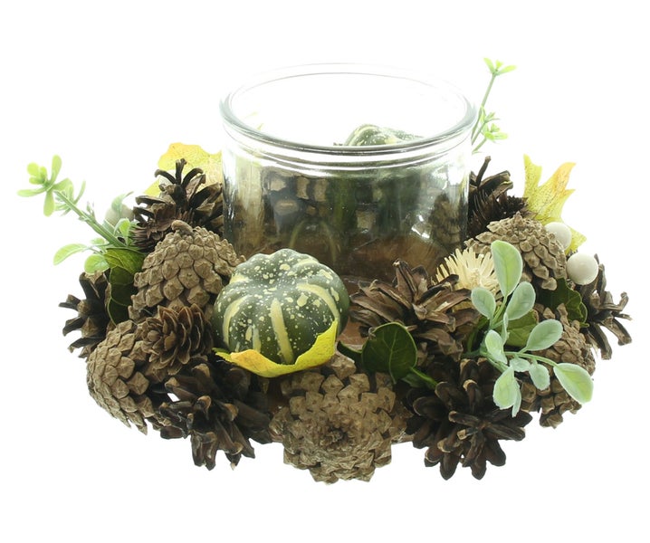 Herbstlicher Kerzenhalter mit Glasbehälter, dekoriert mit Tannenzapfen, künstlichen Blättern und einer kleinen Kürbisfigur.