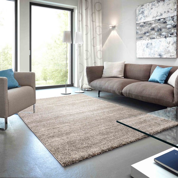 Hochflor-Teppich in einem hellen, modernen Wohnzimmer mit Sofa, Sessel und Glas-Couchtisch.