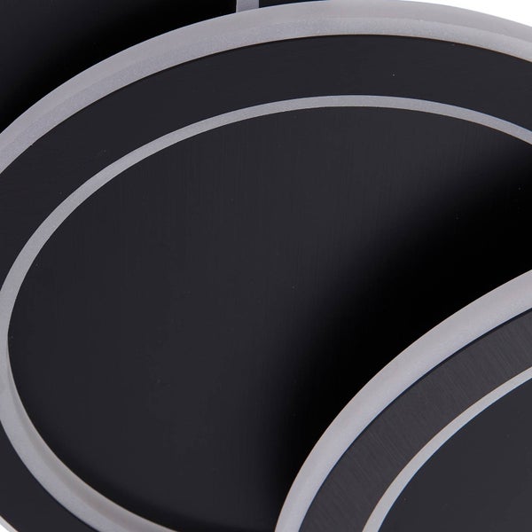 Detailansicht einer runden Leuchte aus schwarzem Metall mit silbernen Konturen.