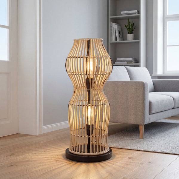 Stehleuchte aus Bambus in Vasenform mit zwei Leuchtmitteln in einem hellen Wohnzimmer neben einem Sofa.