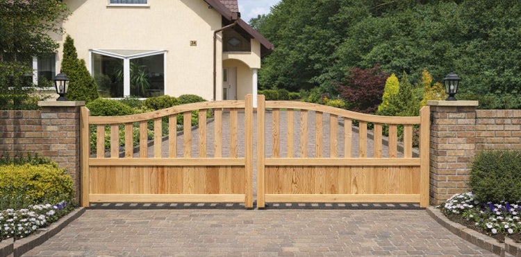 Hölzernes Einfahrtstor mit Ziegelsteinpfosten vor einem Haus