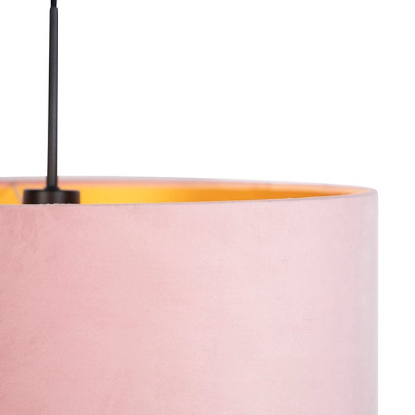 Detail eines zylindrischen Lampenschirms aus rosa Samt mit goldener Innenseite und schwarzer Aufhängung.