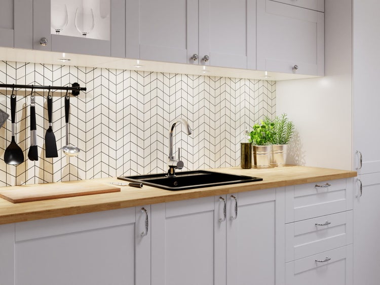 Moderne helle Küche mit hellgrauen Schränken, Holz-Arbeitsplatte, schwarzer Spüle und Rückwand mit Zickzackmuster.