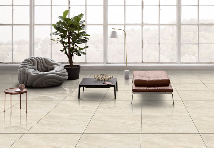 Heller, gefliester Wohnraum mit Sessel, Tisch, Pflanze und Liege