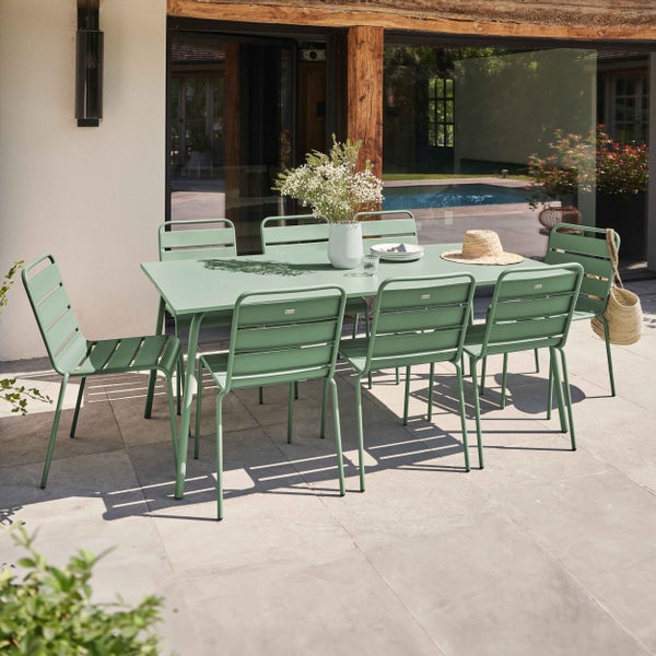 Organisierte Terrasse mit rechteckigem Metall-Gartentisch und sechs Stühlen. Heller Außenbereich mit modernem Haus und Pool im Hintergrund.