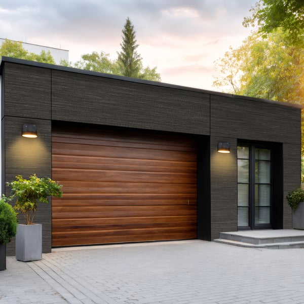 Moderne Garage mit Holztor, Außenbeleuchtung und gepflasterter Zufahrt