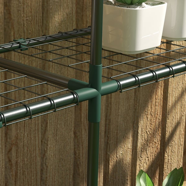 Detailansicht eines Gewächshausregals aus Metallgitter mit Rohrrahmen und Steckverbindung vor einer Holzwand.