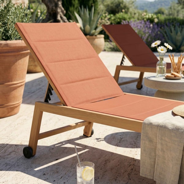 Verstellbare Gartenliege aus Holz mit terracottafarbenem Textilbezug und Rollen auf einer hellen, organisierten Terrasse mit Pflanzen.