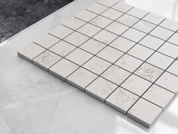 Quadratische Mosaikfliesen in hellgrauer Steinoptik aus Feinsteinzeug.