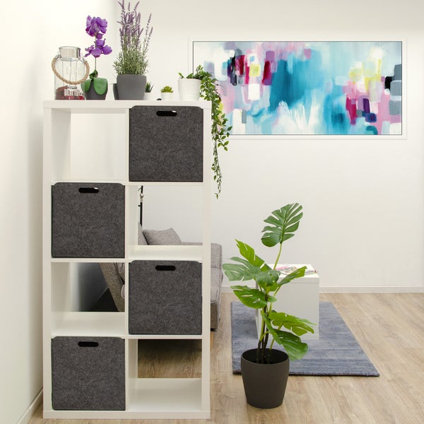 Weißes Regal mit vier Filz-Aufbewahrungsboxen in einem modern eingerichteten Wohnzimmer mit Pflanzen und abstraktem Wandbild.