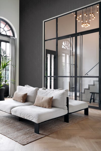 Helles Wohnzimmer mit Sofa, Teppich, Glastür und Zimmerpflanze