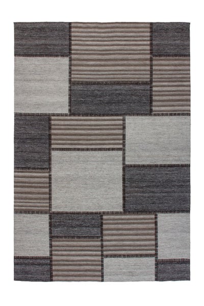 Rechteckiger Teppich mit geometrischem Patchwork Muster aus einfarbigen und horizontal gestreiften Quadraten und Rechtecken.