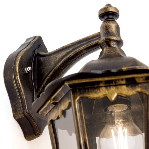 Außenwandleuchte in Schwarz und Gold im antiken Design mit klaren Glasscheiben und leuchtender LED-Filament-Lampe.