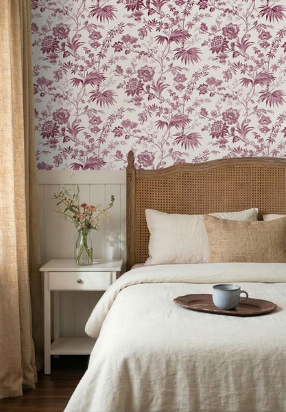 Schlafzimmer mit blumiger Toile-de-Jouy-Tapete, weißer Wandvertäfelung, Holzbett mit Wiener Geflecht und hellem Nachttisch.