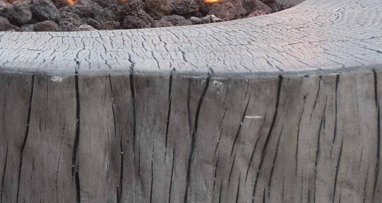Detailansicht einer Feuerschale aus Beton in Holzoptik mit Lavasteinen.
