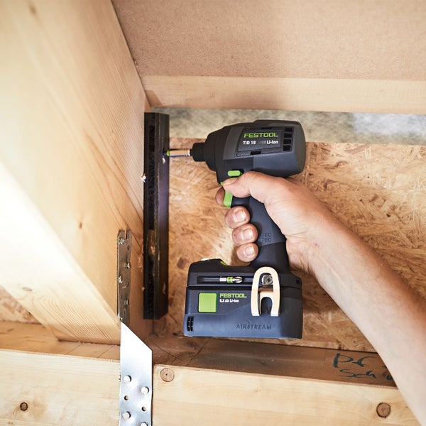 Mann streicht Hauswand stehend auf einer Sprossenleiter