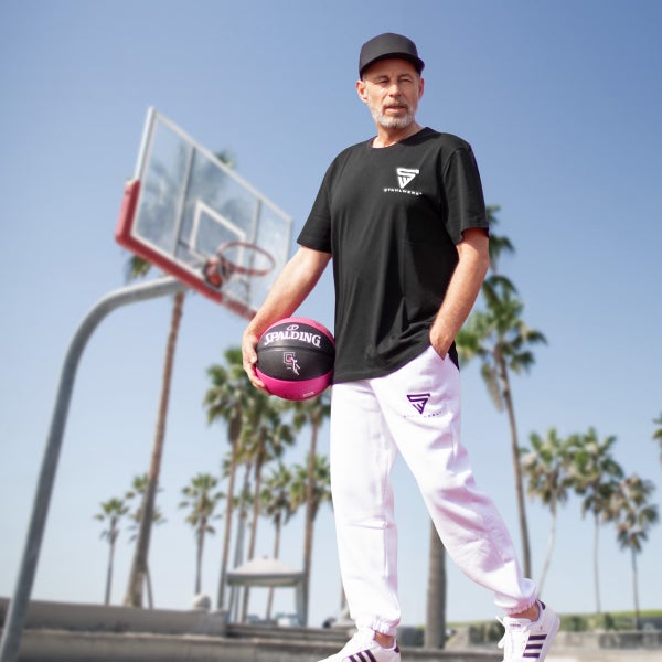 Mann mit Spalding-Basketball, T-Shirt und Jogginghose vor einem Basketballkorb