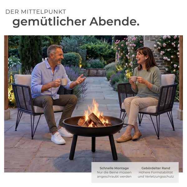 Ein Paar sitzt entspannt in modernen Sesseln um eine brennende Feuerschale aus Metall auf einer gepflasterten Terrasse im Garten.