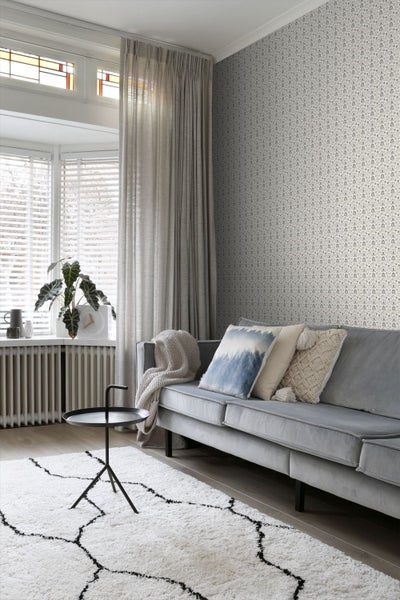 Wohnzimmer mit Sofa, Vorhängen und gemusterter Tapete