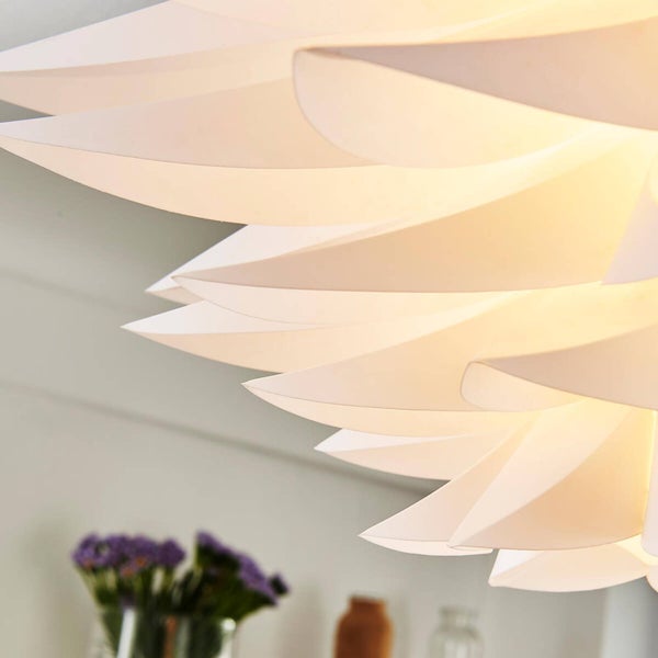 Detailansicht einer modernen Pendelleuchte mit fächerförmigen, weiß leuchtenden Lamellen aus Kunststoff.