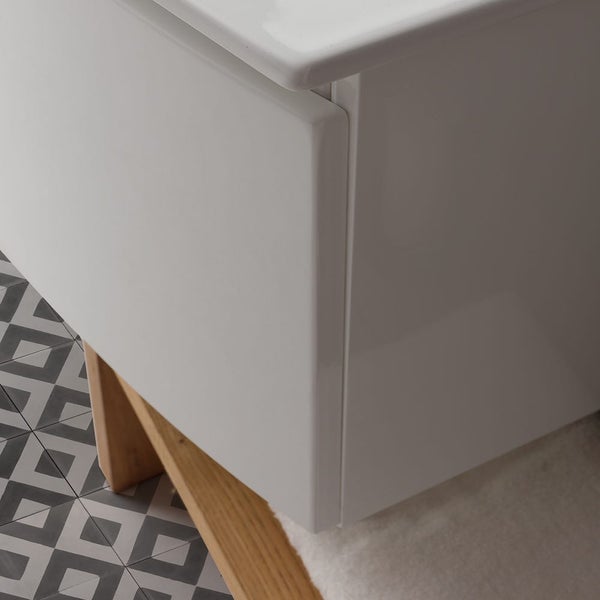 Detailansicht eines weißen Waschtischunterschranks mit Holzgestell und geometrischen Fliesen