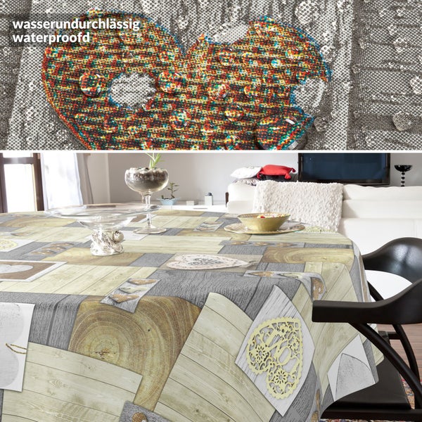 Rundes Tischtuch mit Patchwork-Muster in Holzoptik und Herzmotiven, wasserundurchlässige Oberfläche, auf einem Esstisch in einem hellen Wohnzimmer.