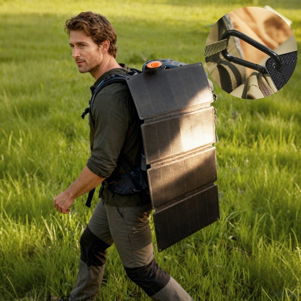 Wanderer mit Rucksack auf einer Wiese und daran befestigtem faltbarem Solarmodul inklusive Detailansicht eines Karabiners.