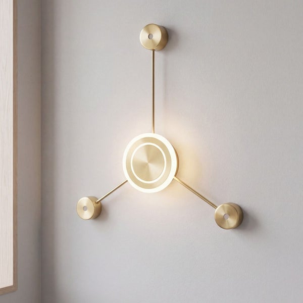 Moderne Wandleuchte aus messingfarbenem Metall mit drei Armen und kreisförmigem Leuchtelement.