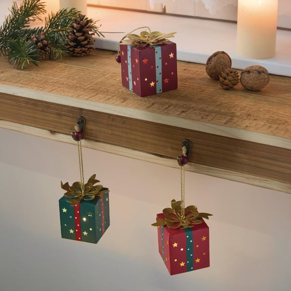 Drei dekorative Weihnachtsgeschenk Anhänger mit LED Beleuchtung und Sternenmuster zur weihnachtlichen Dekoration auf einem Holzbrett