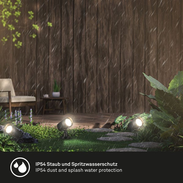 Drei leuchtende Gartenstrahler auf einer nassen Rasenfläche bei Regen vor einer Holzwand mit Möbeln, IP54 Schutz gegen Staub und Spritzwasser.