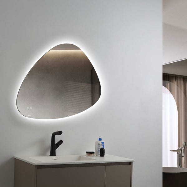 Organisch geformter Badezimmerspiegel mit LED Beleuchtung über einem Waschtisch mit schwarzer Armatur in einem modernen Badezimmer.