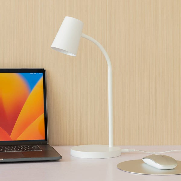 Weiße Schreibtischlampe mit flexiblem Hals und rundem Sockel auf einem hellen Schreibtisch neben einem Laptop und einer Maus.