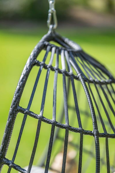 Detailansicht eines Hängesessels aus Kunststoffgeflecht mit Metallaufhängung im Garten.