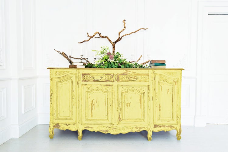 Gelber Vintage-Schrank mit dekorativen Elementen und natürlicher Dekoration