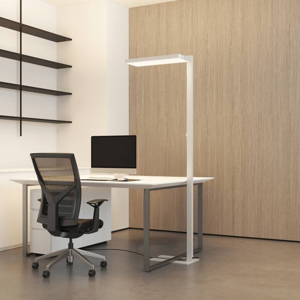 Modernes Büro mit weißer LED-Stehleuchte, minimalistischem Schreibtisch und ergonomischem Bürostuhl vor einer Wand in Holzoptik.