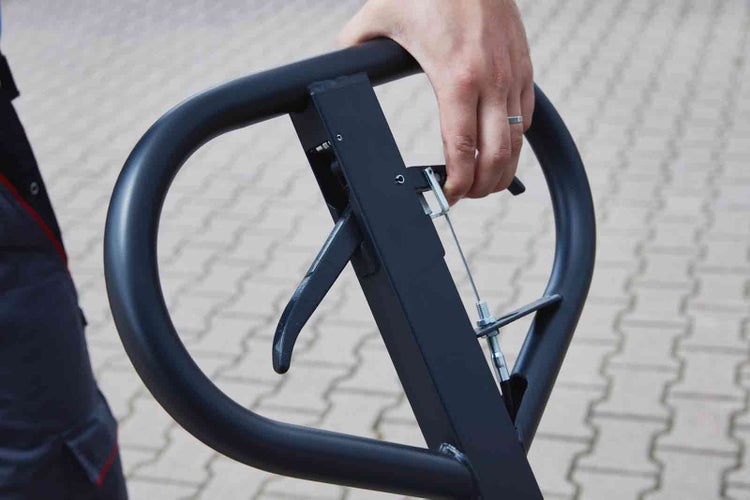 Hand betätigt den Hebel am schwarzen Metallgriff eines Hubwagens.