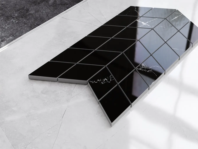 Schwarze Mosaikfliesen in Rautenform mit Marmoroptik, angeordnet im Chevron-Muster.