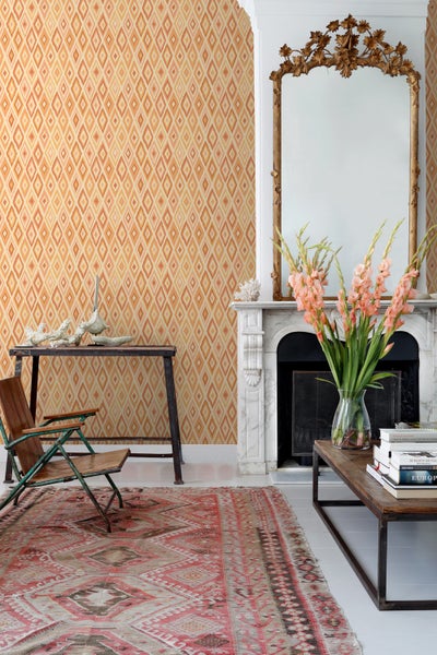 Innenraum mit gemusterter Tapete, Tisch, Stuhl, Teppich und Kamin