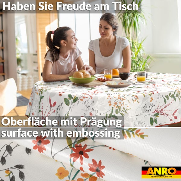 Runde Tischdecke mit floralem Muster und geprägter Oberfläche in einer hellen Wohnküche. ANRO Deutsche Manufaktur Logo.