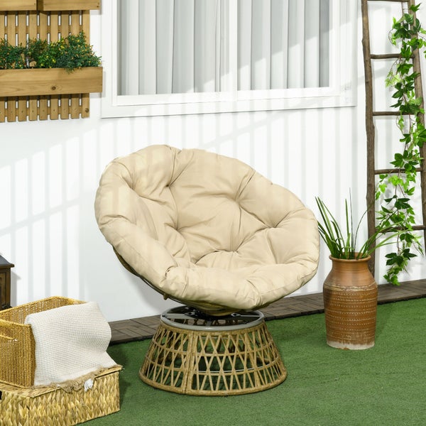 Papasansessel mit beigefarbenem Kissen und Geflechtgestell auf einer hellen Terrasse mit Pflanzen und Dekoration.
