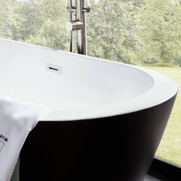 Freistehende Badewanne mit Armatur vor einem bodentiefen Fenster mit Blick ins Grüne