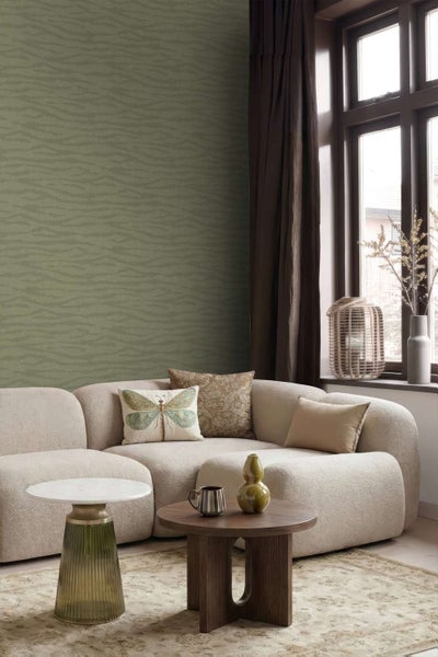 Wohnzimmer mit olivgrüner Tapete mit wellenförmigem Texturmuster, modernem beigem Sofa, Holztisch und dekorativen Wohnaccessoires.