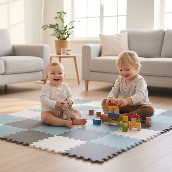 Zwei Kinder spielen auf einer gepolsterten Spielmatte aus ineinandergreifenden Schaumstoffteilen in einem hellen Wohnzimmer.