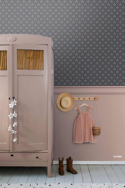 Wandgestaltung mit floral gemusterter Tapete und rosa Wandfarbe, dazu ein Kleiderschrank aus Holz und eine Hakenleiste im Vintage-Stil.