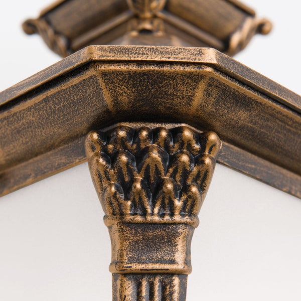 Detailansicht des verzierten Metallrahmens und der dekorativen Säule einer Außenleuchte mit strukturierter Oberfläche.