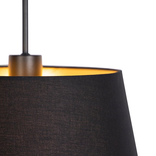 Nahaufnahme einer Pendelleuchte mit dunklem Textilschirm und goldfarbener Innenseite.