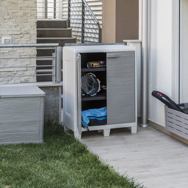 Gartenschrank mit geöffneter Tür auf einer Terrasse, mit Gegenständen gefüllt