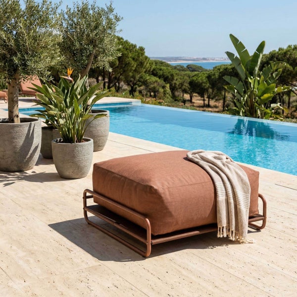 Moderner Outdoor-Hocker mit terracottafarbenem Polster auf einem Metallgestell neben einem Pool auf einer hellen Steinterrasse.