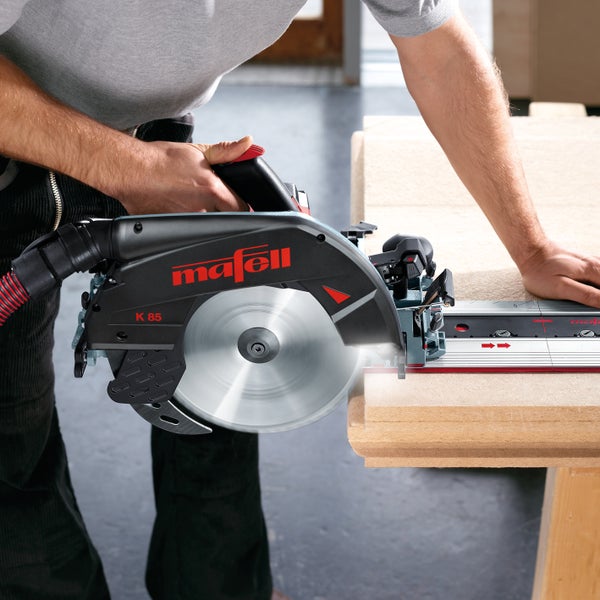 Handwerker bei der Arbeit mit einer Mafell Handkreissäge K 85 auf einer Führungsschiene beim Sägen einer Holzplatte