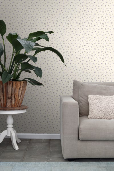 Raumansicht mit Blumentapete, Topfpflanze auf Beistelltisch und Sofa